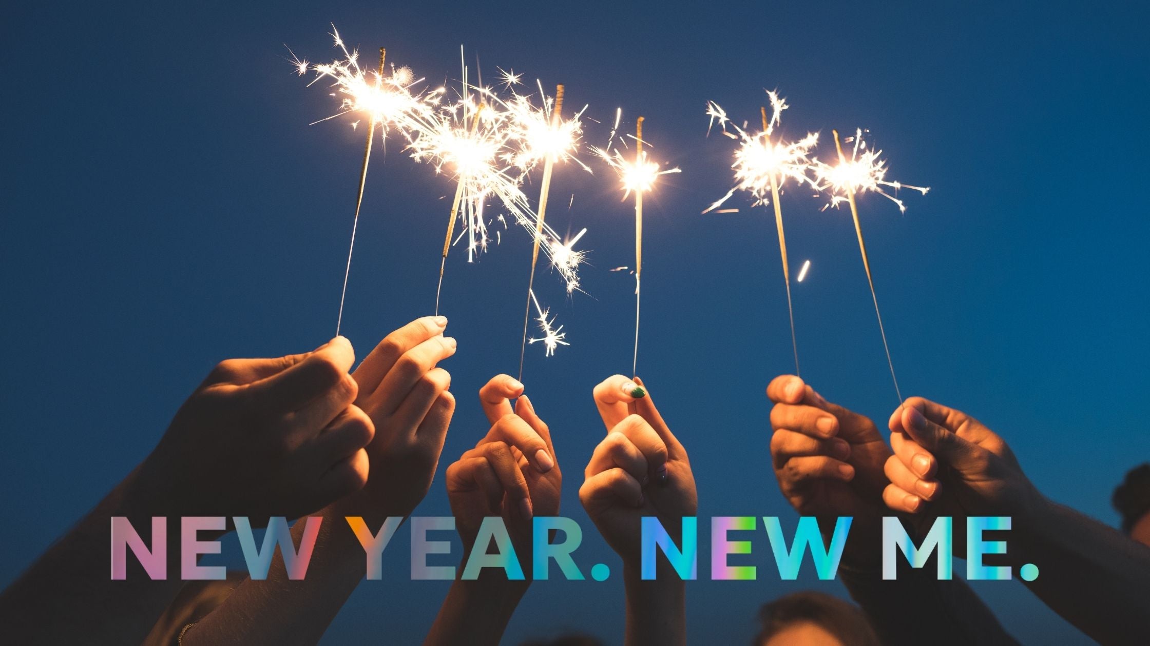 Mehrere Hände halten Wunderkerzen in den Abendhimmel, darunter der Schriftzug „New Year. New Me.“ – Symbolbild für Neuanfang, Neujahrsvorsätze und bewussten Start ins neue Jahr.