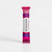 Natürlicher Lippenbalsam von BEN&ANNA mit Himbeerduft, zeigt den Lippenbalsam in einer transparenten Verpackung mit Himbeeren.