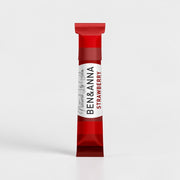Natürlicher Lippenbalsam von BEN&ANNA mit Erdbeerduft, zeigt den Lippenpflegestift in einer offenen Verpackung.