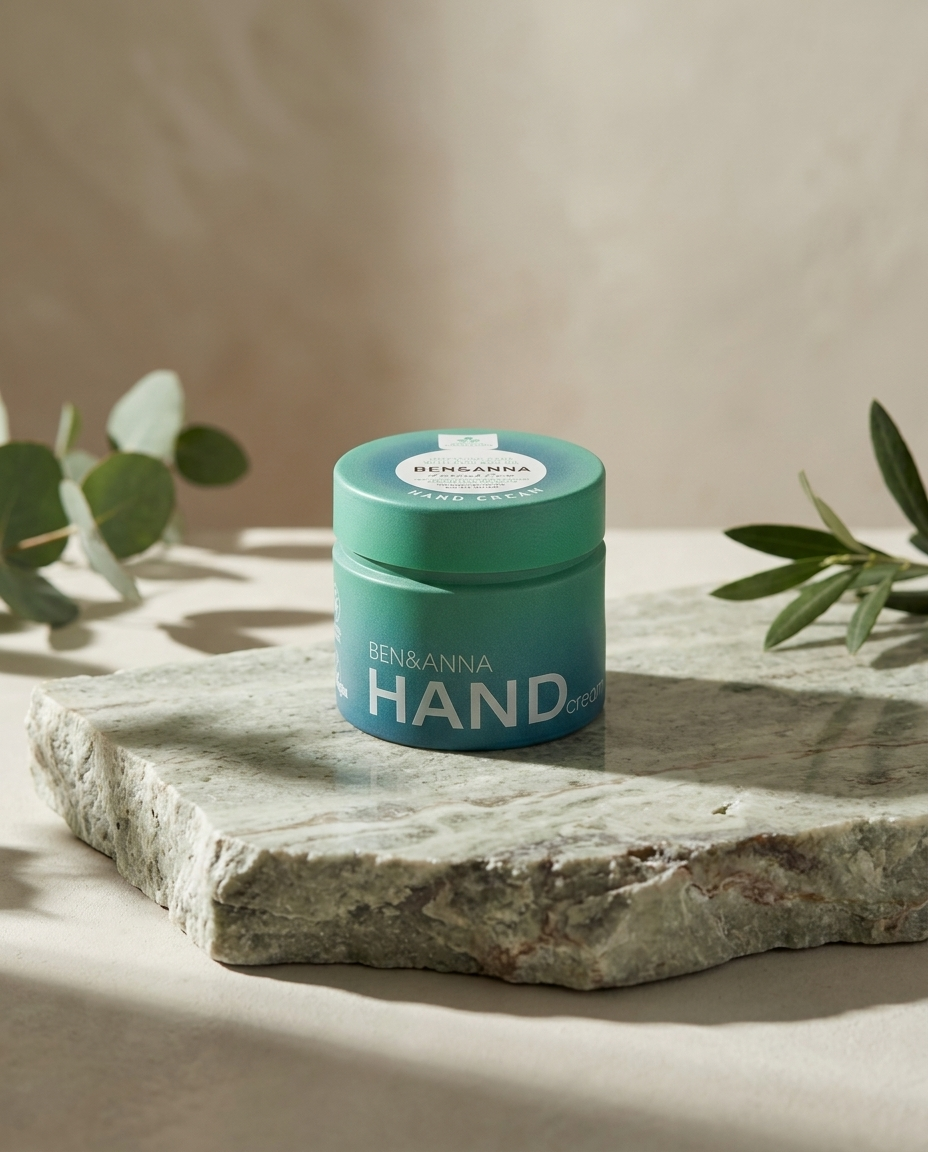 Ben & Anna Intensive Care Handcreme im türkisen Glastiegel auf einer grünen Natursteinplatte mit Eukalyptuszweigen